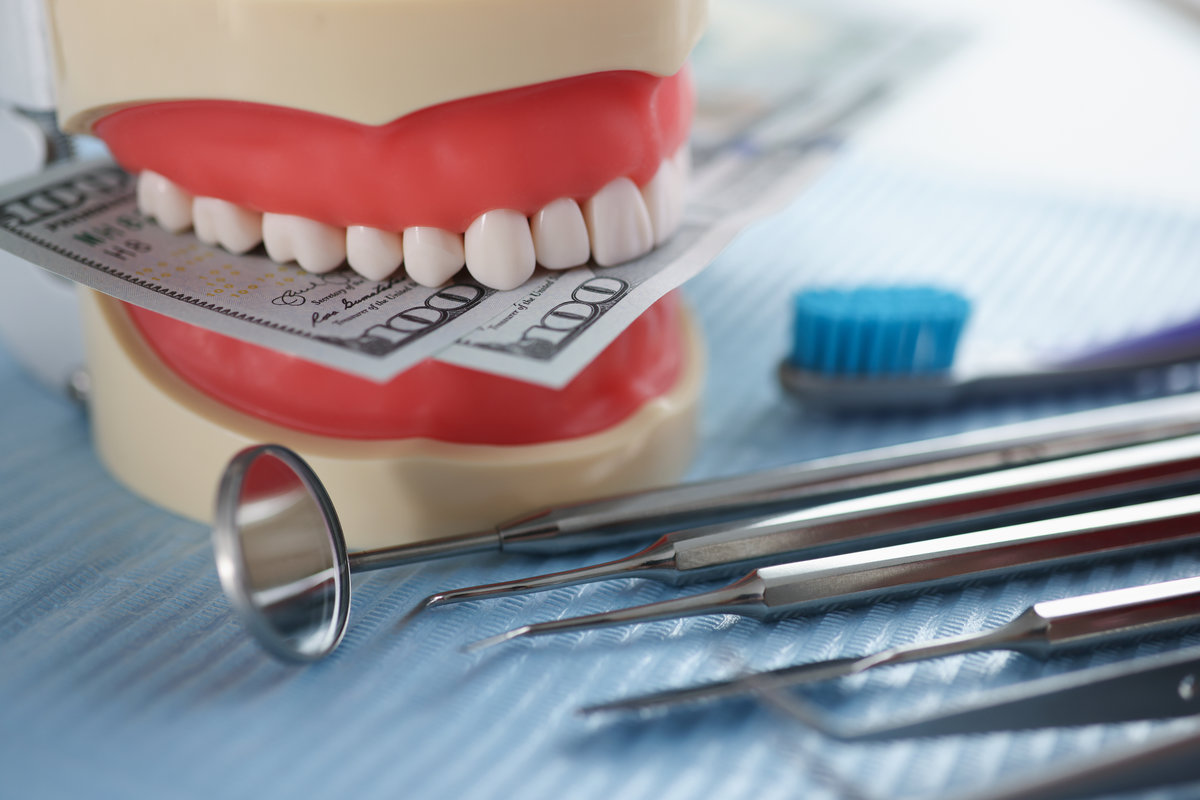 Artificial jaw mockup with money and dental instrument on table. Cost of stomatological services concept